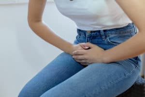 Woman suffering urinary incontinence and holding stomach